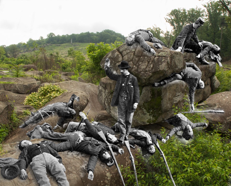 A number of men posing as dead soldiers lie across and underneath rocks in the Slaughter Pen.