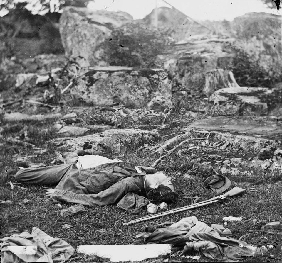 A dead soldier lies in front of rocks near Devil’s Den.
