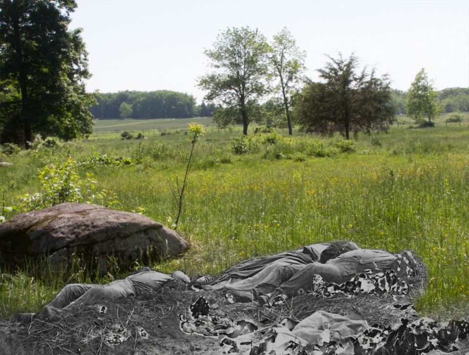 This view looks southwest, away from the Rose Woods. Three dead soldiers lie next to a large rock.