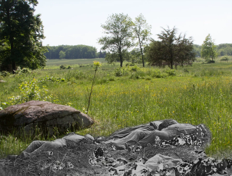 This view looks southwest, away from the Rose Woods. Three dead soldiers lie next to a large rock.
