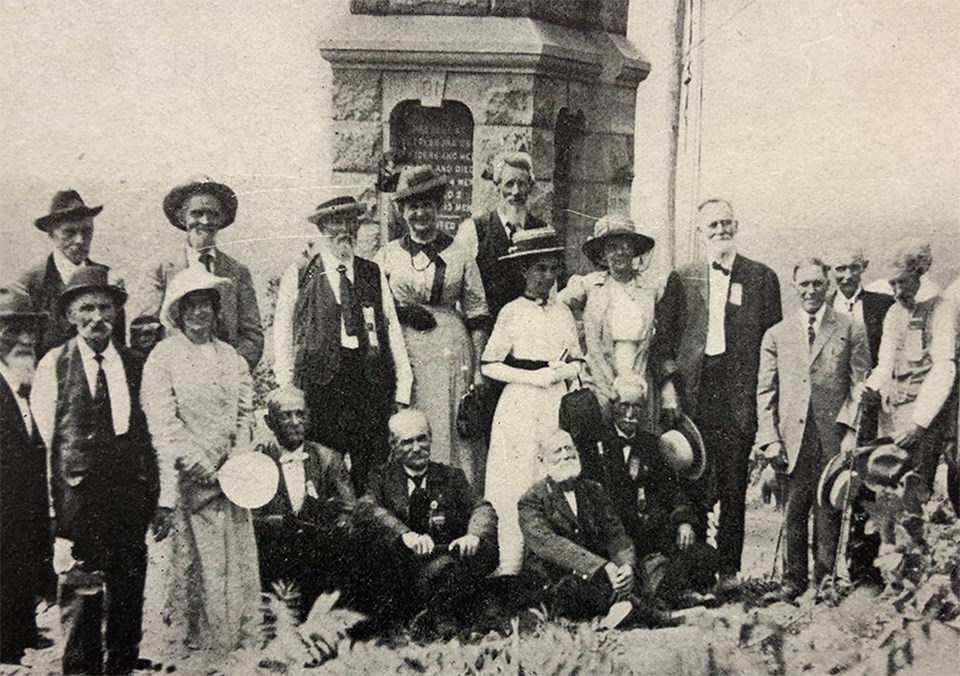A crowd of people pose for a picture in front of the 91st Pennsylvania monument on the summit of Little Round Top.