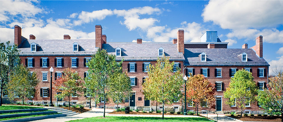A brick building with the signage "H & H Paper Co." The windows are in various states from being boarded up to bricked in. The rooftop is flat.