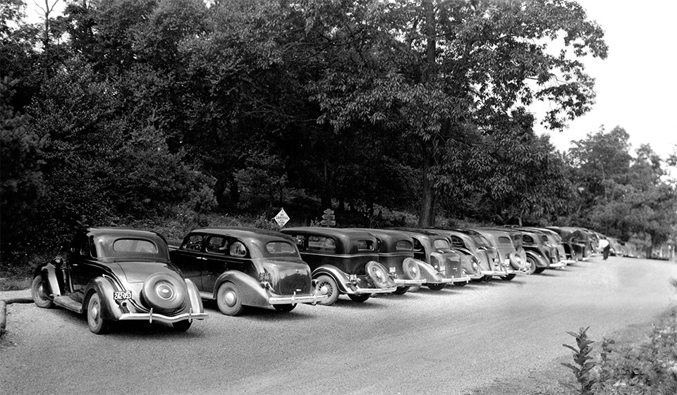 A black and white photograph of a parking lot with cars in it.