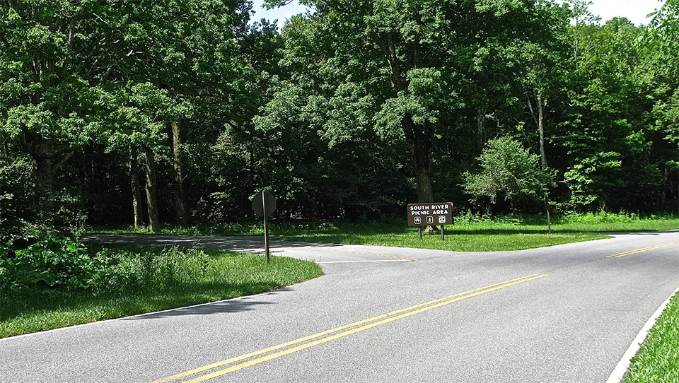 A black and white photograph of a road with a fork in it and bare ground all around.