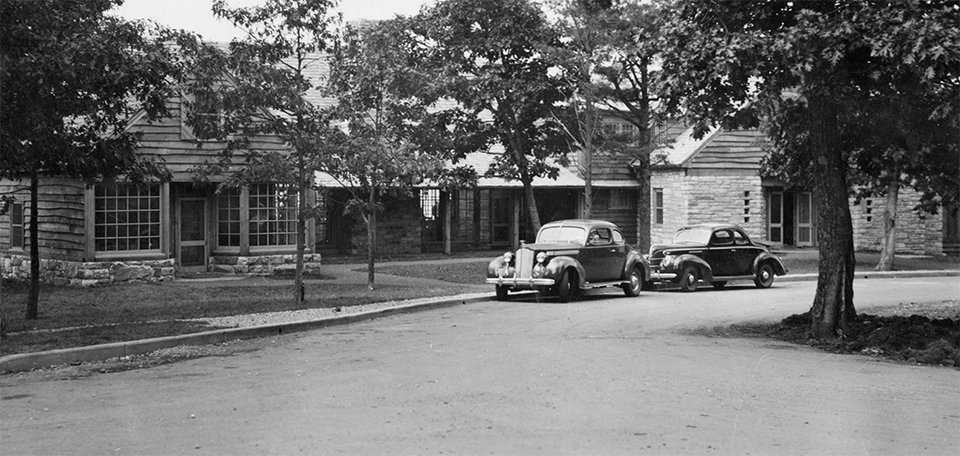 A black and white photograph of a lodge with a driveway.