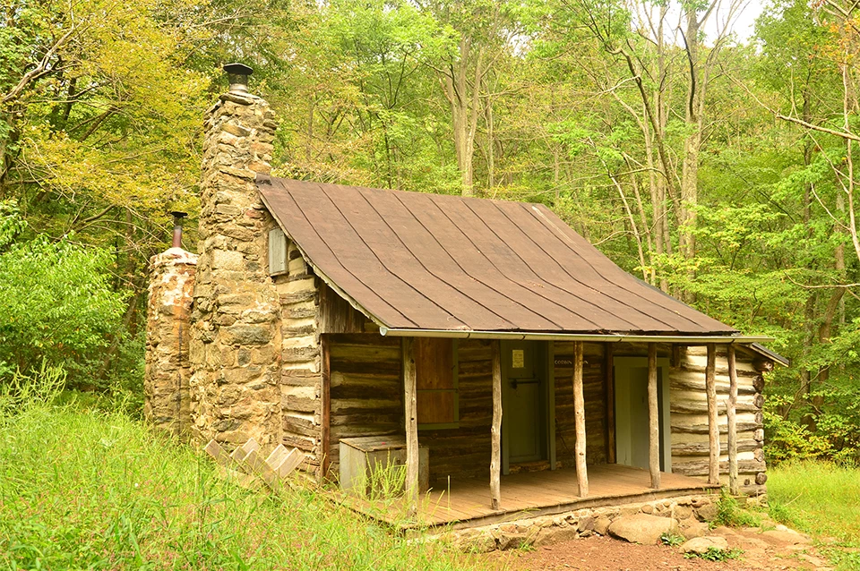 A black and white photograph of a log cabin in the woods.