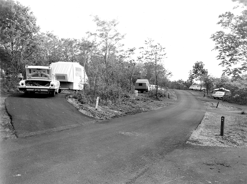 A black and white photograph of a road through a campground.