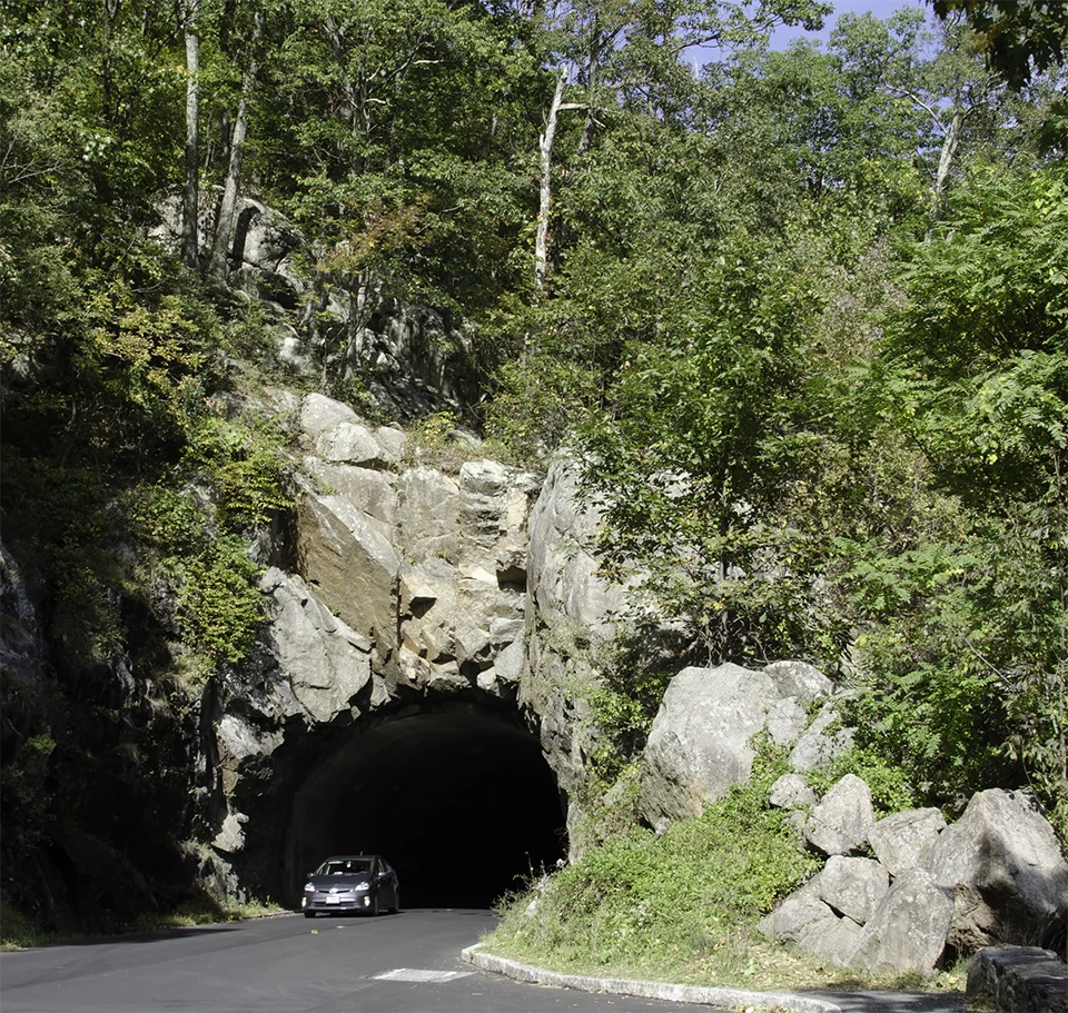 A black and white photograph of a car coming through a tunnel.
