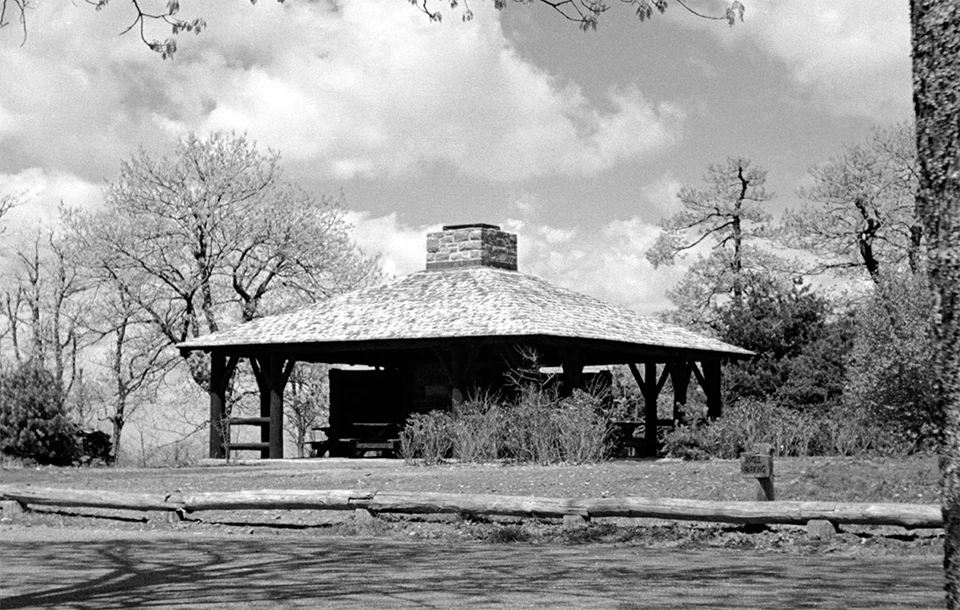 A black and white photograph of a picnic shelter.