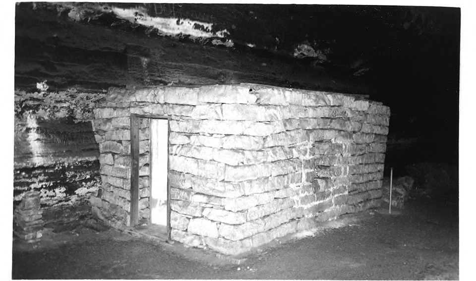 Ten young women and one man posed on and around a small stone building inside Mammoth Cave.