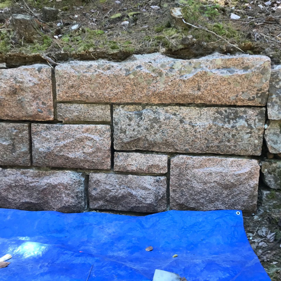 a blue tarp below a stone wall
