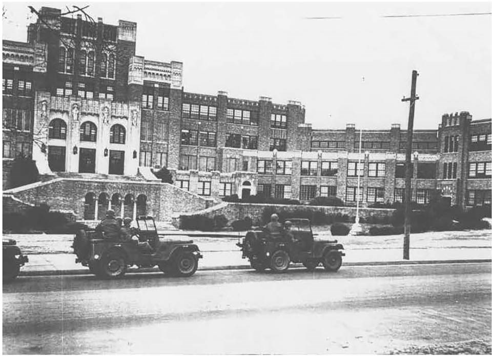 National Guard troops in military jeeps parked on the street in front of the entrance to Central High School