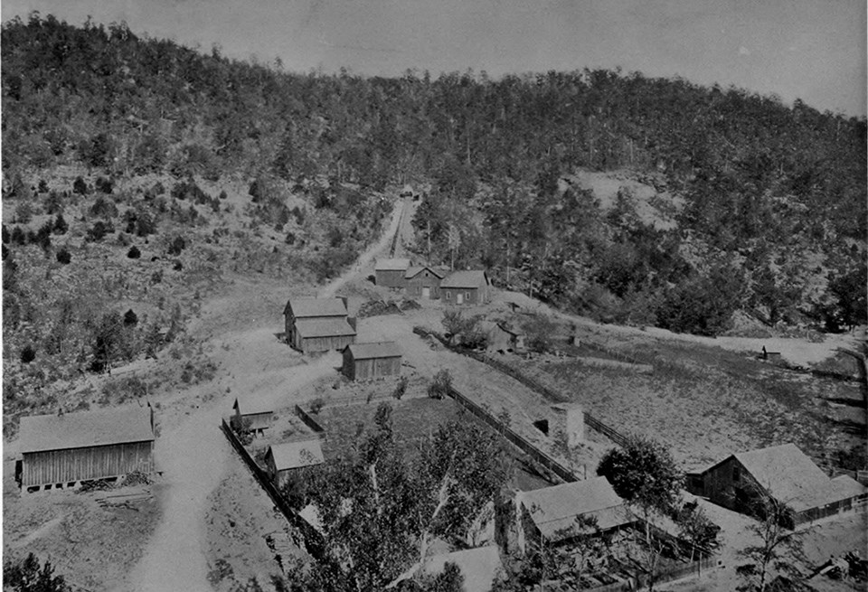 Historical photograph of roads weaving through a mining town, composed of wooden structures in a rural area