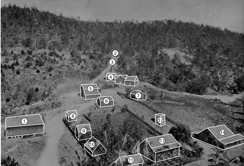 Historical photograph of roads weaving through a mining town, composed of wooden structures in a rural area