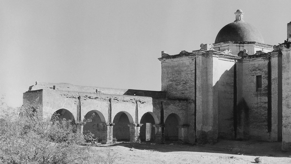 historic photo of arched walkway with drainage canales extending out from church