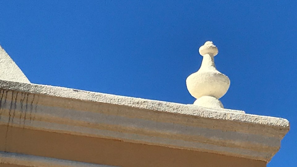 historic photo of ornate carved finial (decorative post) on roofline