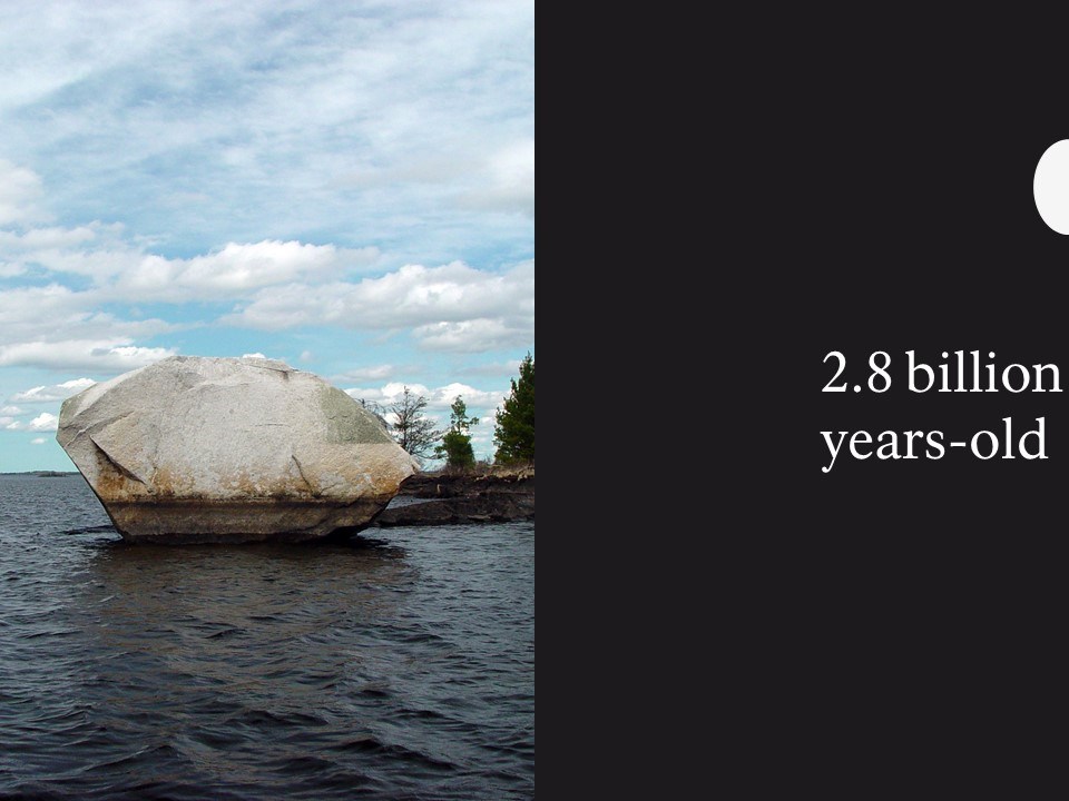 A glacial erratic (large rock) in sitting in a large body of water.