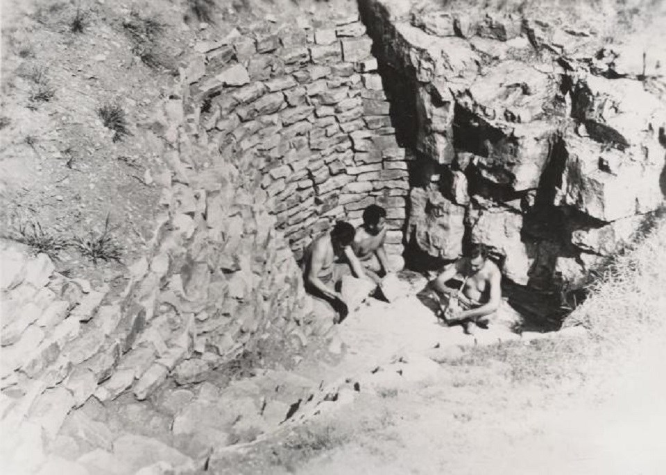 Black and white historic photo of several people quarrying rock