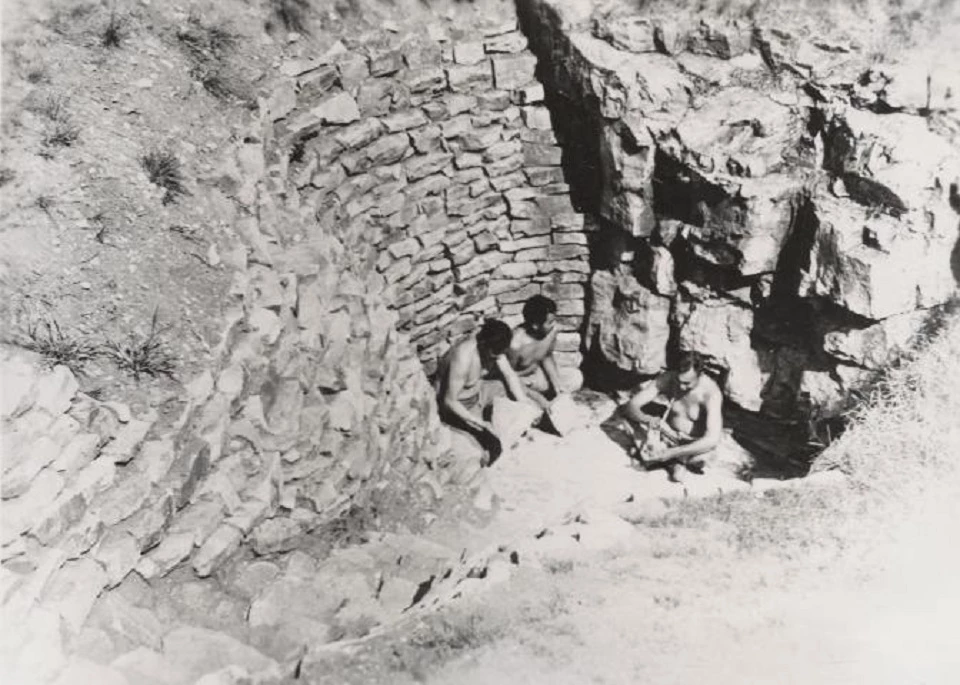 Black and white historic photo of several people quarrying rock