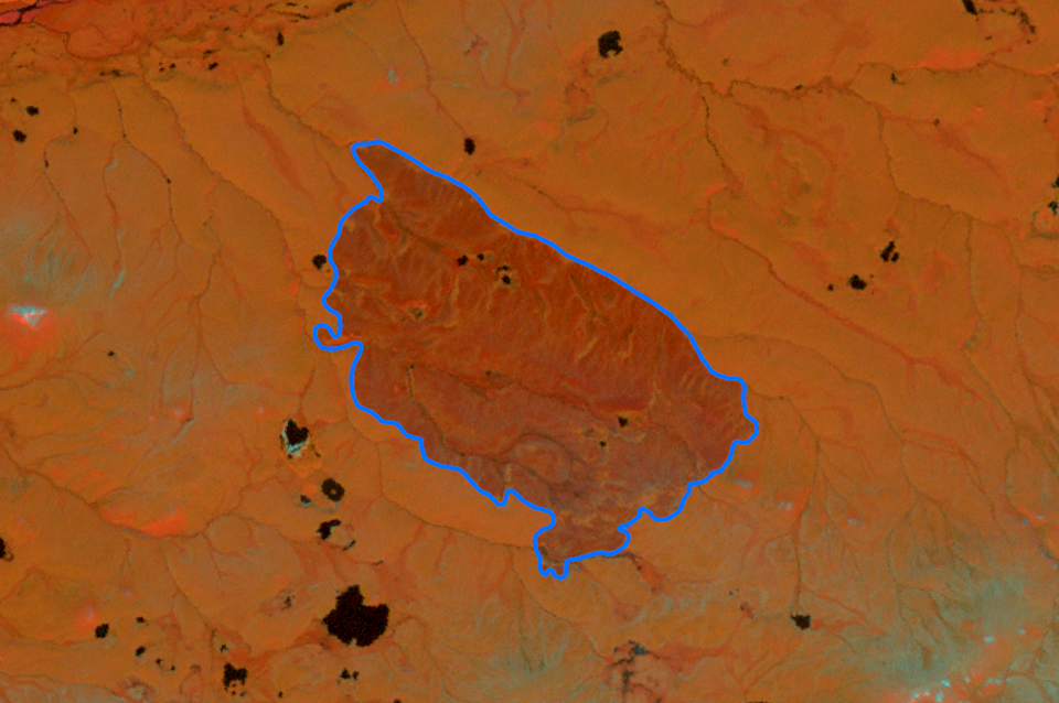 A Landsat image in orange hues of a fire scar with a dashed line denoting the original perimeter