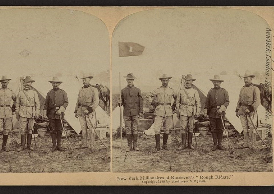 An historic photograph of five Rough Riders standing in a line in front of a camp tent