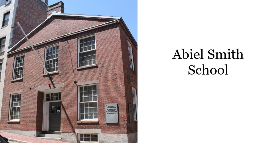 A 2 story brick building. On the front, there are 5 windows visible - 3 on the 2nd story, and 2 on the 1st. There is a door and window on the 1st floor and 2 windows spaced evenly above on the 2nd floor. On the right, text reads "Abiel Smith School"