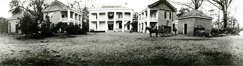 Historic image of the backyard of the Melrose Estate with a horse and cart in a building-encircled courtyard.