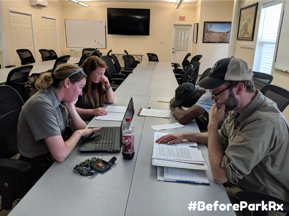 Four people unhappily working at a table