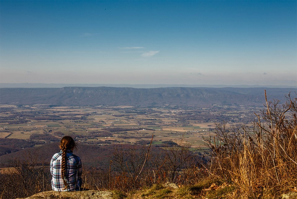 Person sitting overlooking a valley