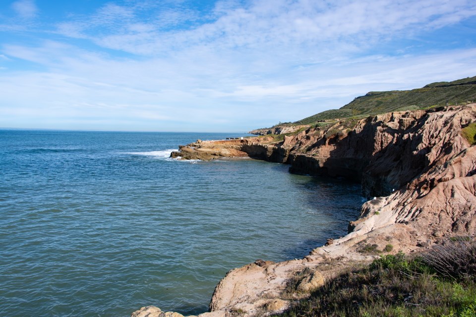 Ocean water covering rocky shoreline adjacent to cliffs