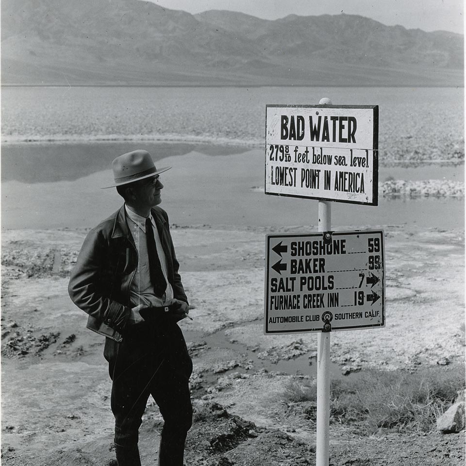 A ranger in 1935 stands next to a sign that reads Badwater 279 feet below sea level