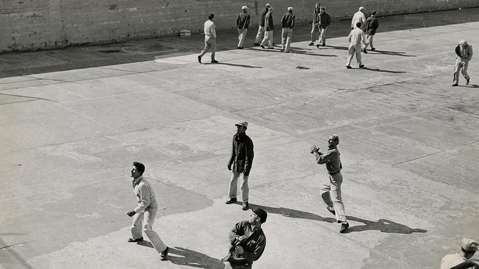 two people walk across asphalt prison rec yard