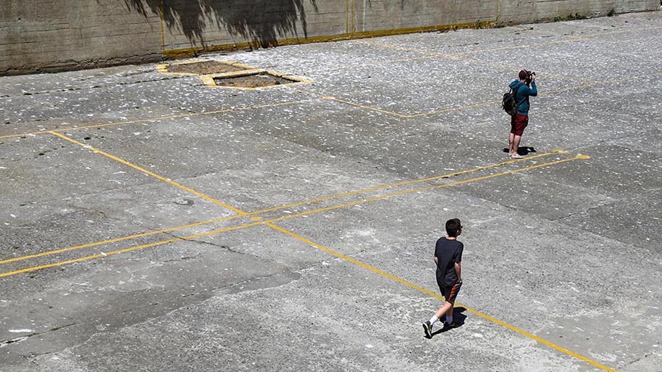 two people walk across asphalt prison rec yard