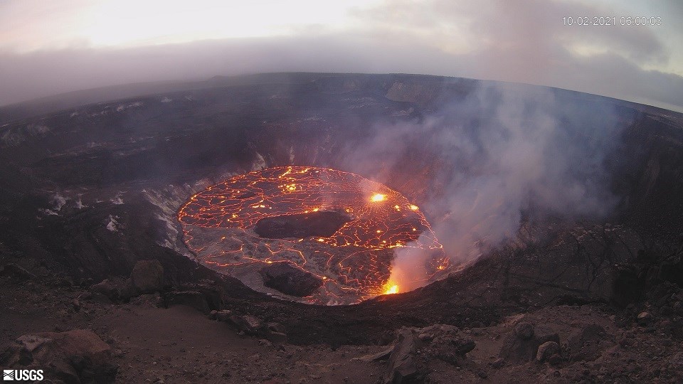 View looking down into deep large crater with dark brown surface and large flat bottom.