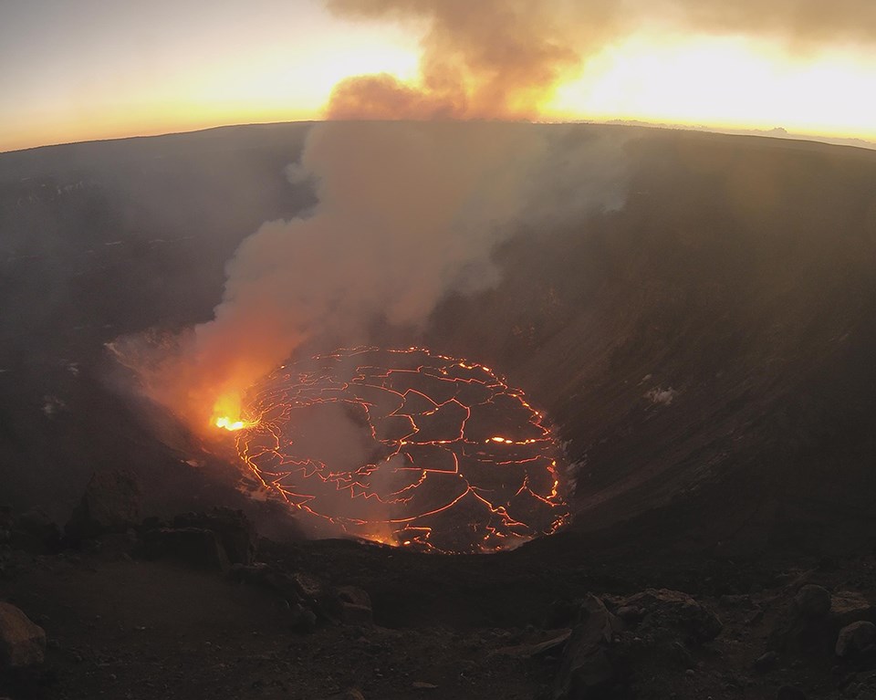 Steaming and glowing lava lake in a volcanic crater