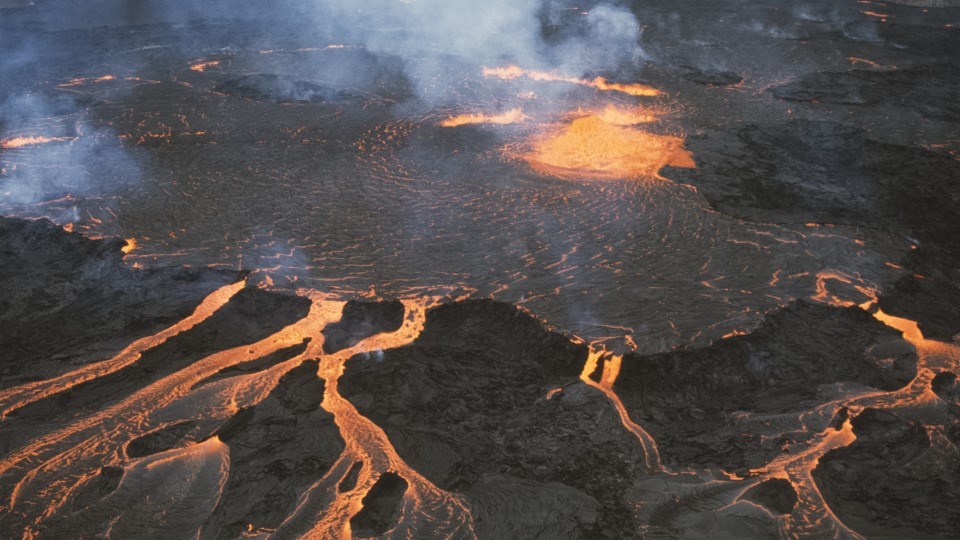 Lava pools and flows across a dark landscape