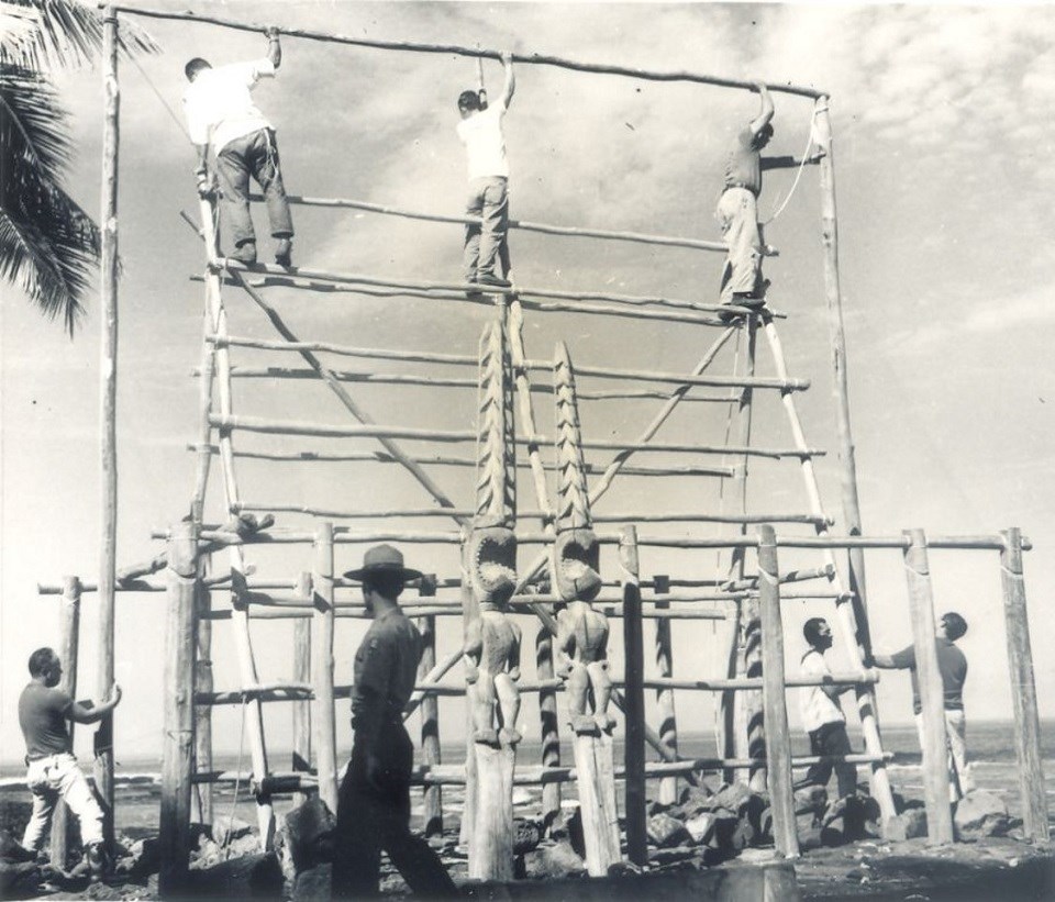 Men build the scaffolding for the original reconstruction of Hale o Keawe, Park Ranger walking in front