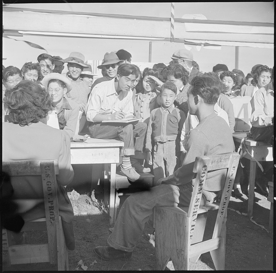Tule Lake Relocation Center, Newell, California. Harvest Day Festival. An artist sketches one of the festive throng in the concessionary.