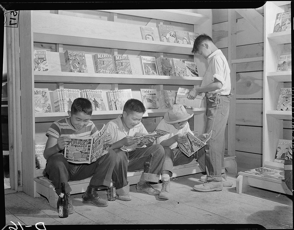 Four little evacuees from Sacramento, California, read comic books in the newstand at this War Relocation Authority center for evacuees of Japanese descent.