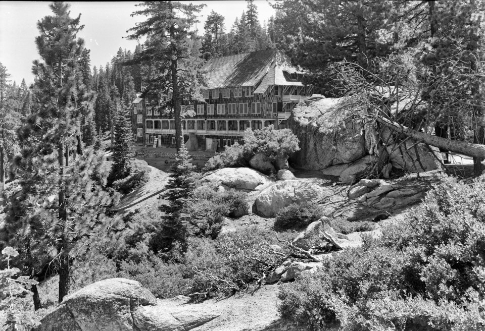 A building on a slope surrounded by trees and boulders.