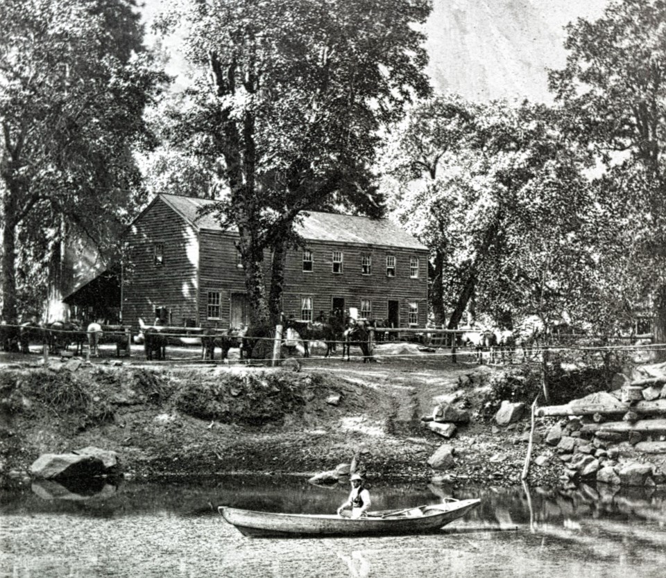 Person in canoe on river with building behind