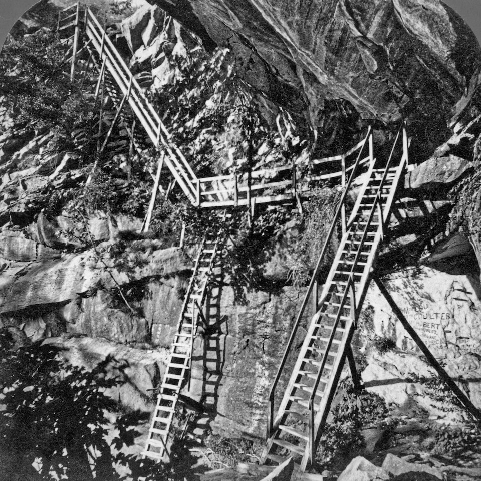 Wooden ladders and walkways climbing up a cliff.