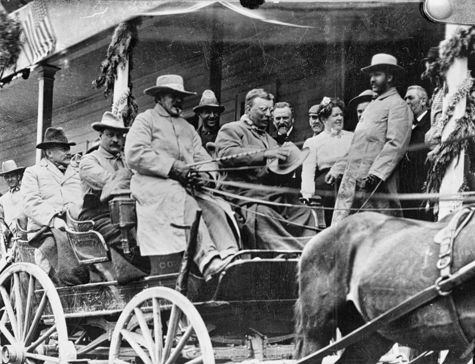 Stagecoach with men and horses in front of a building.