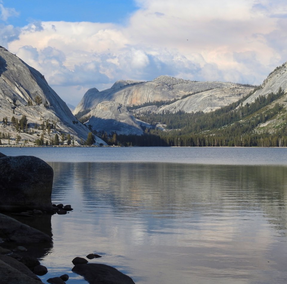 Painting of a partially snow-covered lake with mountains and a rising moon in the background