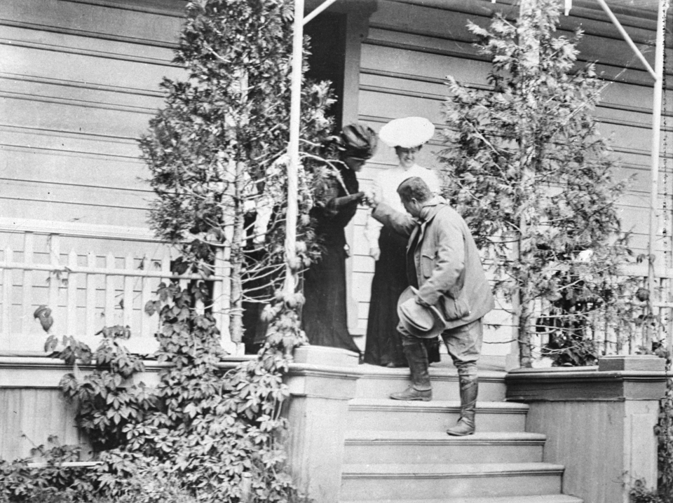 President Theodore Roosevelt greeting two women at the top of stairs.