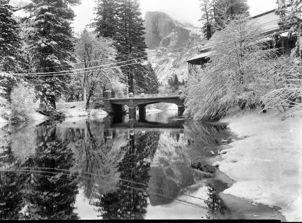 A river and a bridge in winter with a building on the edge of the river.