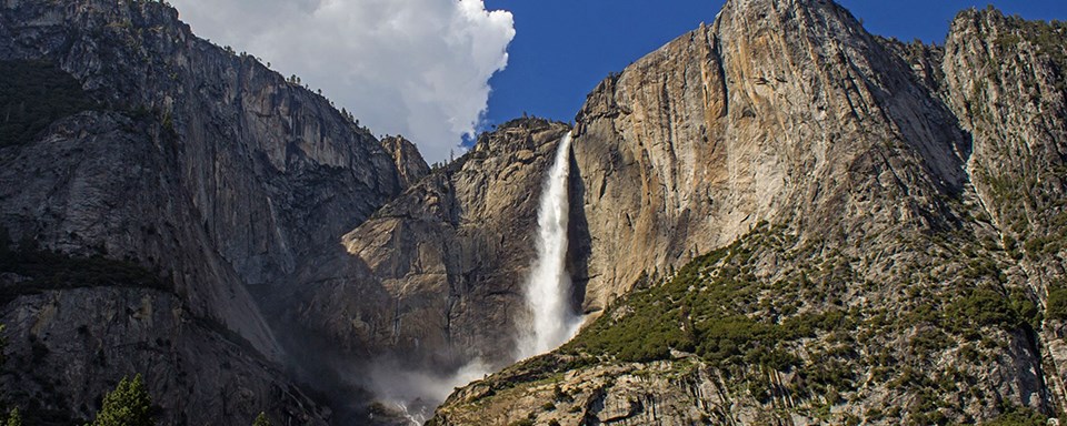 Photograph of tall waterfall pouring down granite cliff.