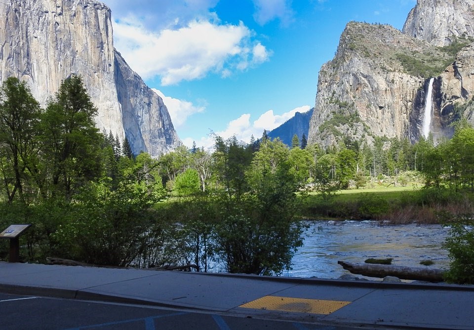 A group of people next to a river with cliffs and waterfalls behind.