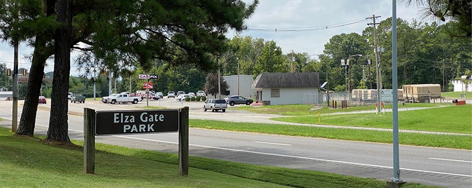 Black and white photo of a car driving through a guarded security gate.