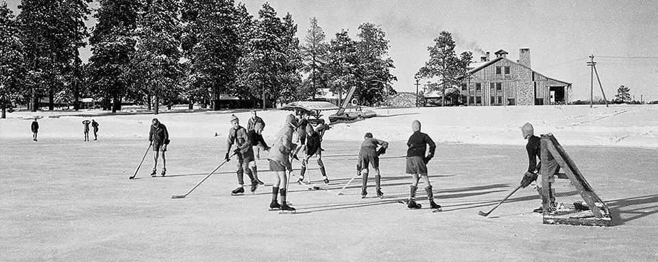 A black and white photo of kids skating on ice.